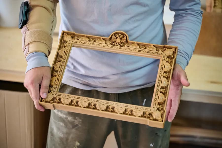 Мастер держит резную наградную рамку из массива